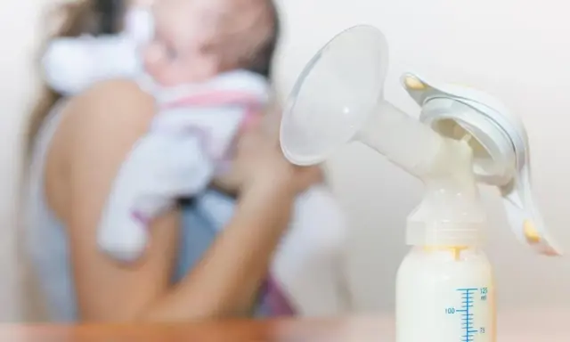 Laktator z butelką mleka, w tle mama z dzieckiem. Zastanawiasz się, ile trwa nawał mleczny?