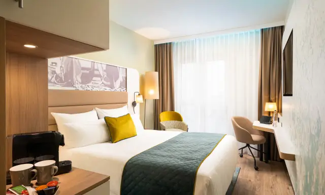 Modern Hotelzimmer mit Bett, Schreibtisch und Kaffeemaschine.