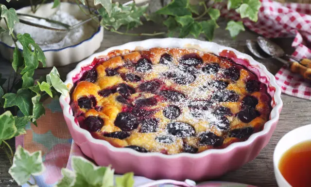 Un délicieux clafoutis aux prunes, saupoudré de sucre glace, prêt à être dégusté.