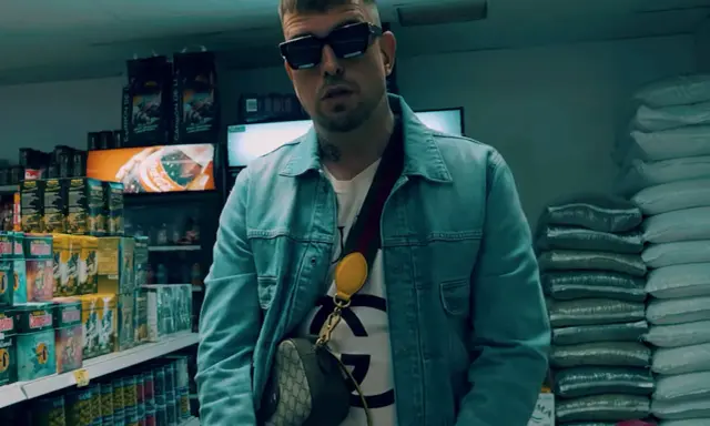 Malik Sentino w okularach i dżinsowej kurtce stoi w sklepie, otoczony towarem.