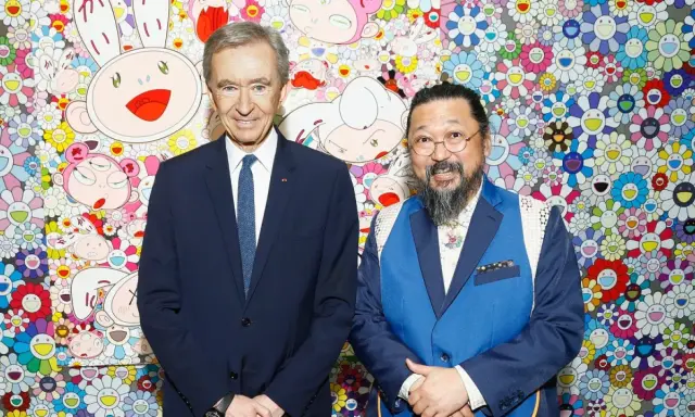Two billionaire art collectors, Bernard Arnault and Takashi Murakami, pose in front of Murakami's signature smiling flower art.