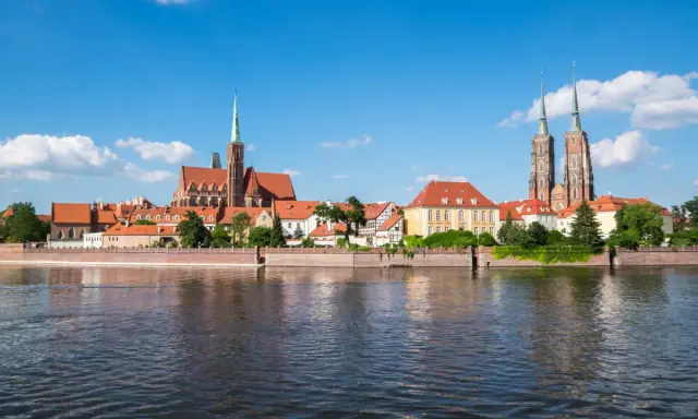 Widok na Ostrów Tumski we Wrocławiu, perłę Dolnego Śląska, z rzeką w tle.