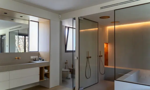 Moderno baño con ventana, ducha de cristal, bañera y lavabo doble.