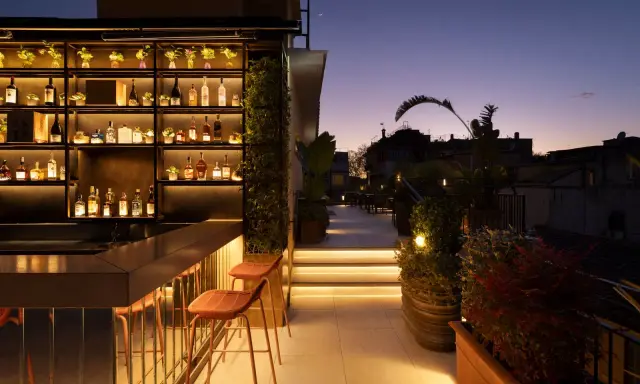 Terrazza panoramica con bar illuminato e sedie, ideale per scoprire le cose da fare a Roma nel weekend.