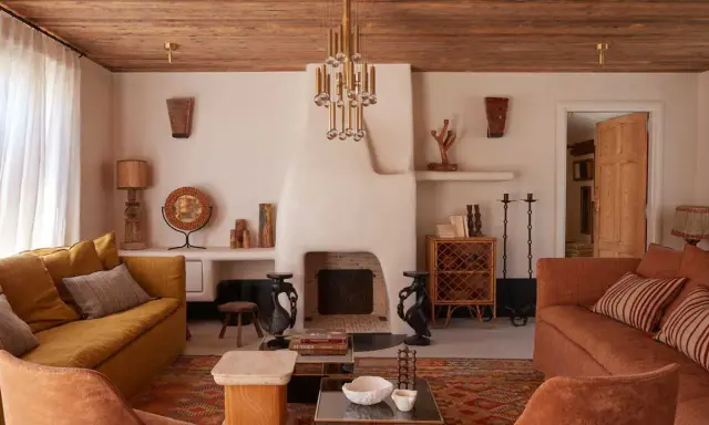Ambiance chaleureuse dans cet **intérieur maison île de Ré**. Canapés confortables, cheminée imposante et plafond en bois créent un cocon douillet.