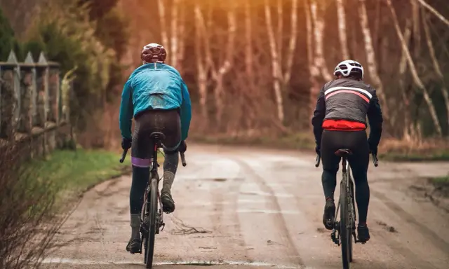 Dwóch rowerzystów w jesiennych strojach, idealnych na 15 stopni. Lekka kurtka i długie spodenki to dobry wybór na przejażdżkę.
