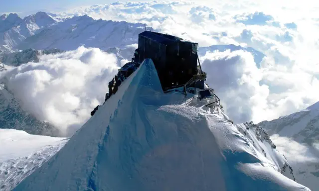 Il rifugio più alto d'Italia, incastonato su una vetta innevata, domina un mare di nuvole.