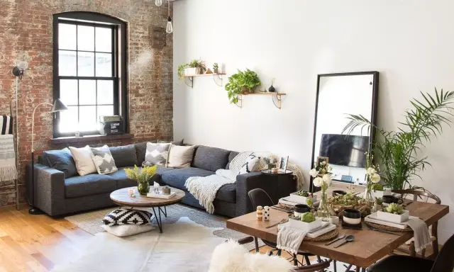 Sofá gris, mesa de centro redonda, mesa de comedor de madera y espejo de cuerpo entero crean un ambiente de **estilo cozy**.