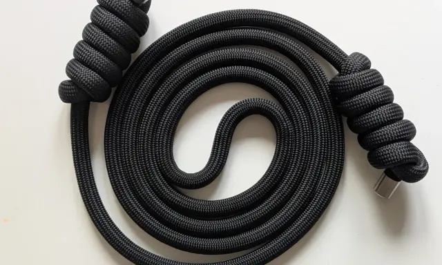 Schwarzes Seil mit Metallenden, kunstvoll zu einer Spirale gewickelt. Der rope flow erzeugt ein faszinierendes Muster.