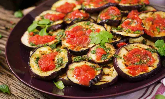 Fette di melanzane grigliate condite con salsa di pomodoro e basilico, un gustoso piatto di melanzane alla pizzaiola.