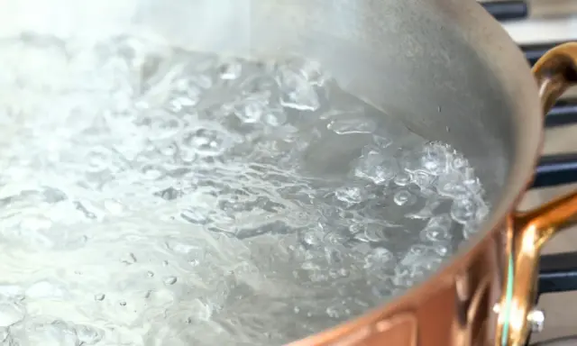 Woda wrze w miedzianym garnku, tworząc bąbelki. Czas gotowania zależy od tego, ile się gotuje woda.