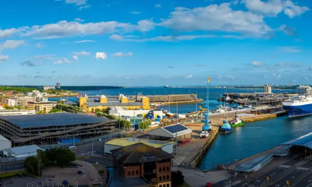 Vista panoramica del **southampton porto** con navi, gru e edifici moderni sotto un cielo azzurro con nuvole bianche.