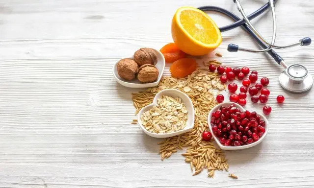 Sposób babci na obniżenie cholesterolu: orzechy, owsianka, żurawina, granat, pomarańcza i suszone morele. Stetoskop symbolizuje zdrowie.