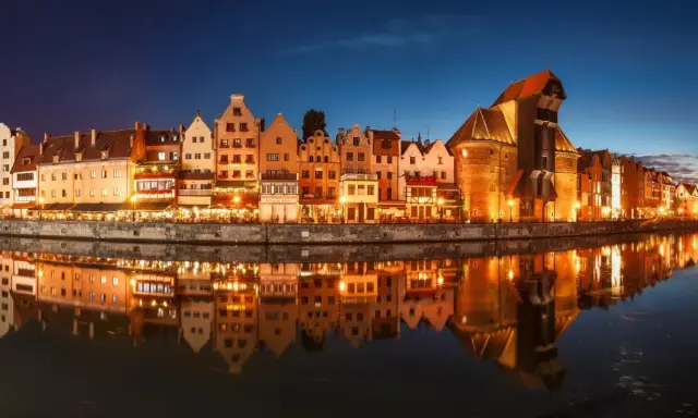 Nadmorska panorama Gdańska nocą, z odbijającymi się w wodzie kamienicami i Żurawiem. Idealne miejsce na zaręczyny Polska.