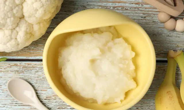 Puré de coliflor listo para servir. Ideas de recetas de coliflor para niños, con plátanos y cuchara.