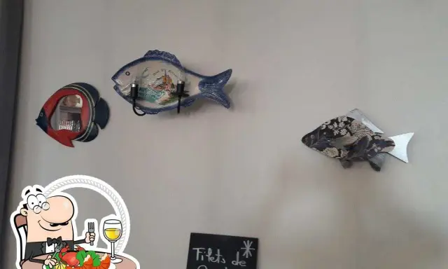 Décoration murale en forme de poisson au restaurant Le Saint Pierre La Tronche. Assiette de fruits de mer et verre de vin.