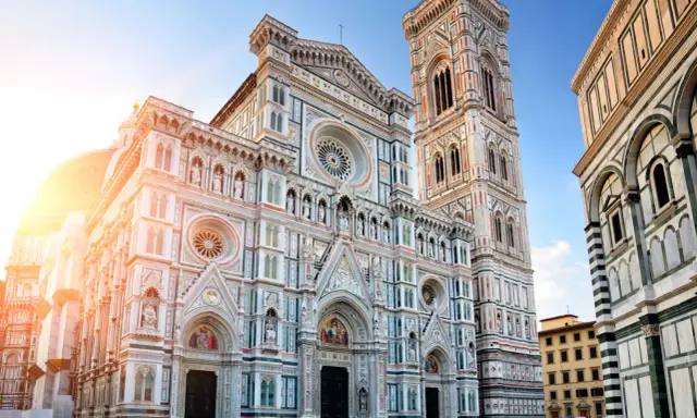 La majestueuse coupole de Florence, le Duomo, se dresse fièrement sous un ciel bleu, baignée par les rayons du soleil.