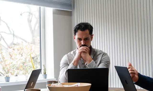 Man denkt diep na over beleid en maatschappij, omringd door laptops en plantjes.