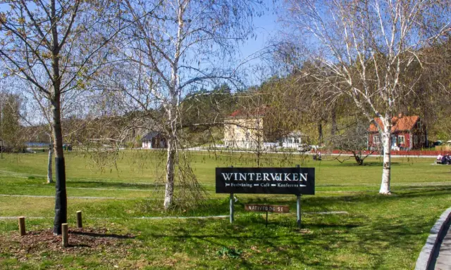 Vinterviken Stockholm, en grönskande park med träd och byggnader. En skylt visar "Winterviken - Festvåning - Café - Konferens".