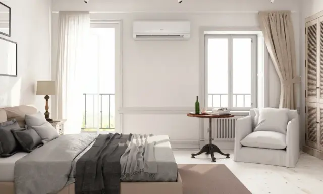 Un dormitorio luminoso con cama, armario de madera y aire acondicionado. La unidad de aire acondicionado está colocada estratégicamente en la pared, mostrando dónde colocar el aire acondicionado en un dormitorio para una climatización óptima.