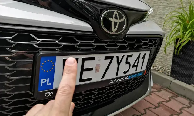Palec wskazujący na tablicy rejestracyjnej samochodu. Czy to zgubiona rejestracja?