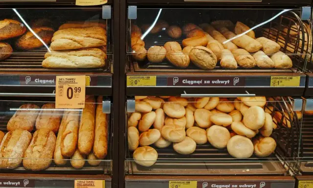Różnorodne bułki i bagietki na półkach sklepowych. Idealne na śniadanie, choć warto sprawdzić ich kcal.