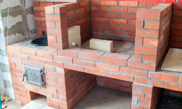 Construcción de diversos tipos de chimeneas de obra, con ladrillos rojos y detalles metálicos.