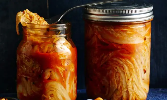 Zwei Gläser mit fermentiertem Chinakohl, bereit für das authentische kimchi rezept original. Ein Löffel ragt aus dem linken Glas.