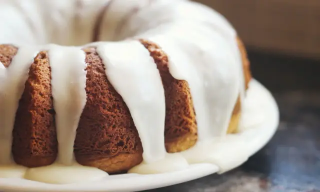 Gâteau moulé, doré, nappé d'un glaçage blanc crémeux. Une invitation à découvrir comment faire du fondant blanc.