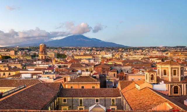 Vista panoramica di Catania con l'Etna sullo sfondo. Tetti rossi, cupole e palazzi storici offrono spunti per le cose da fare a Catania.
