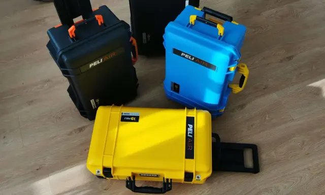 Trzy walizki Peli Air w kolorach czarnym, niebieskim i żółtym. Idealne do przewożenia cennego sprzętu w bagażu podręcznym.