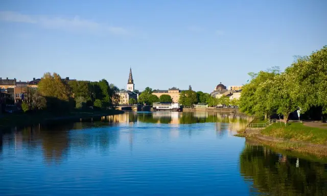 Vacker stad vid vattnet med kyrktorn och gröna träd. Tänk dig att bo på ett mysigt vandrarhem i Torsby och vakna till denna vy.
