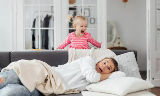Niña emocionada sobre el sofá, mientras su madre se asusta. ¡Un día típico con el horario para niños en casa!