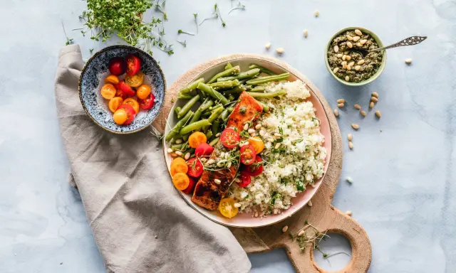 Un délicieux repas parisien : saumon grillé, haricots verts, riz et tomates cerises, accompagné de pesto et de pousses fraîches.