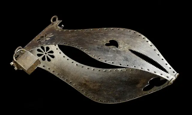 Metalowy pas cnoty, ozdobiony kwiatami i sercem, z ząbkowanym zamknięciem.