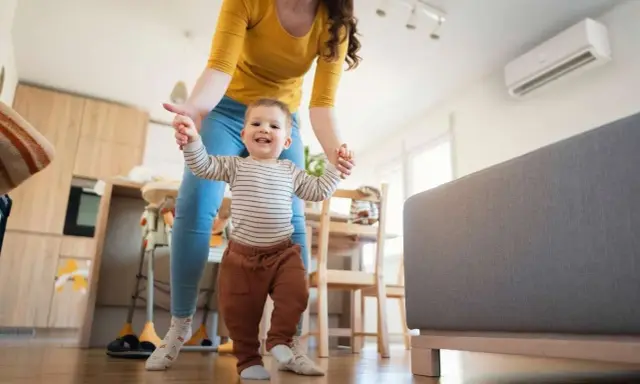 Mamma aiuta il suo bambino a fare i primi passi, con l'aria condizionata neonati che garantisce un clima ideale in casa.