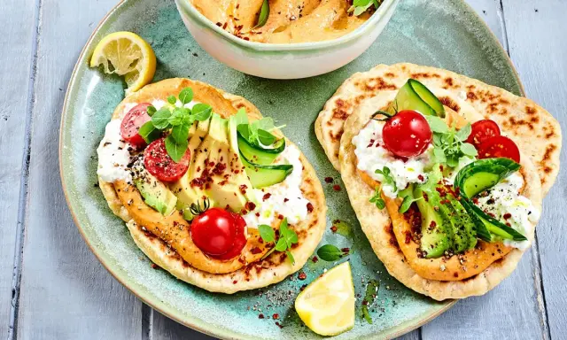 Leckere kalte gerichte ohne kochen: Fladenbrot mit Hummus, Avocado, Tomaten, Gurke und Frischkäse. Garniert mit Kräutern und Zitrone.