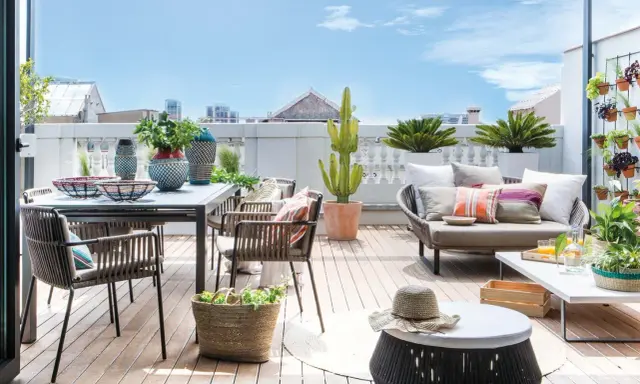 Ideas para decorar una terraza: mesa, sillas, sofá, plantas y cestas crean un espacio acogedor y moderno.