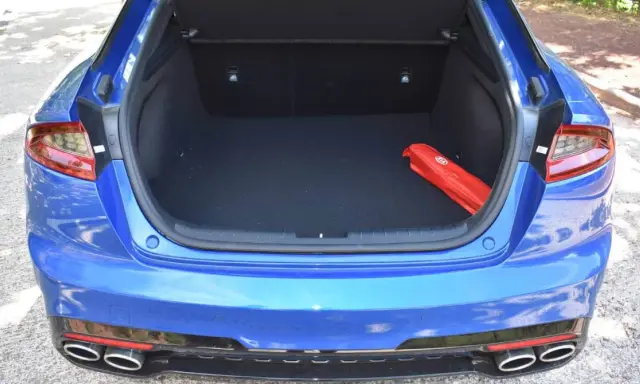 Maletero abierto de un Kia Stinger azul, con un botiquín rojo en el interior.