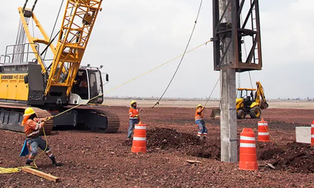 Trabajadores y maquinaria pesada instalan pilotes para cimentaciones profundas en un sitio de construcción.