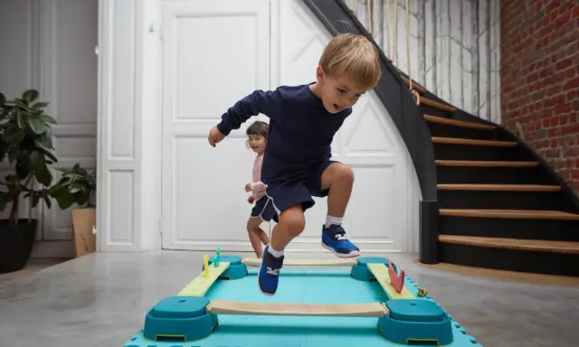 Bambini di 4 anni si divertono con la psicomotricità, saltando su un percorso a ostacoli colorato.