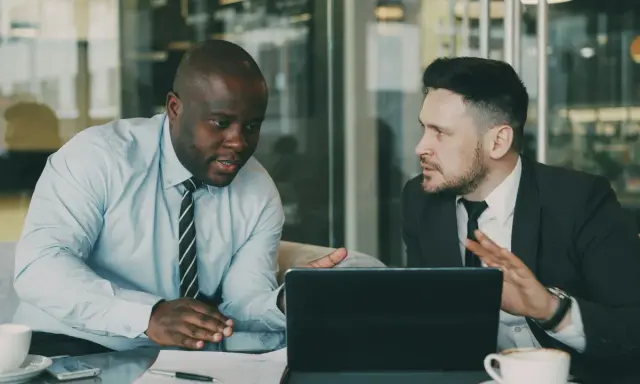 Deux hommes d'affaires discutent d'une nouvelle démarche, synonyme de succès. Ils sont concentrés sur une tablette.