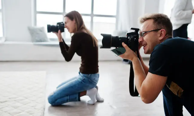 Mężczyzna i kobieta uczą się, jak zostać fotografem, ćwicząc z aparatami w studiu.
