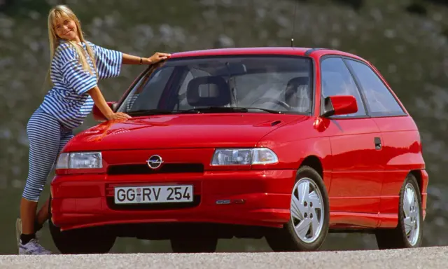 Mujer rubia posa junto a un coche histórico rojo. ¿Cuántos años tiene este coche?