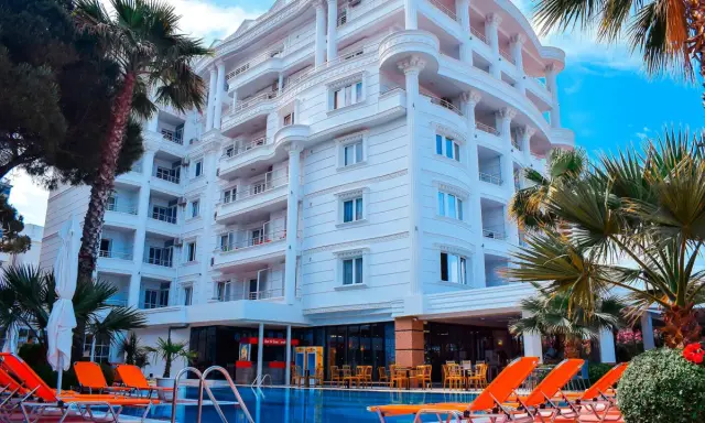Biały hotel z balkonami i basenem, otoczony palmami. Idealne miejsce na fafa mel holiday.