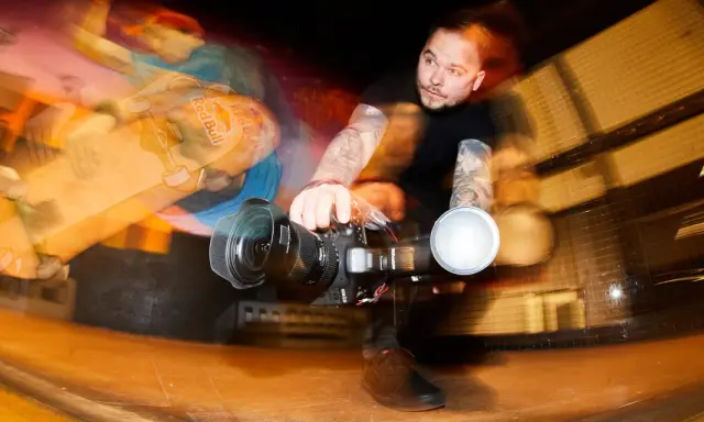 Fotograf z tatuażami łapie ruch deskorolkarza z Red Bulla. Krótki czas naświetlania uchwycił dynamiczną akcję.