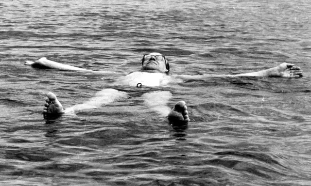 Tage Erlander, statsminister, flyter avslappnat på rygg i vattnet, med armarna utsträckta.