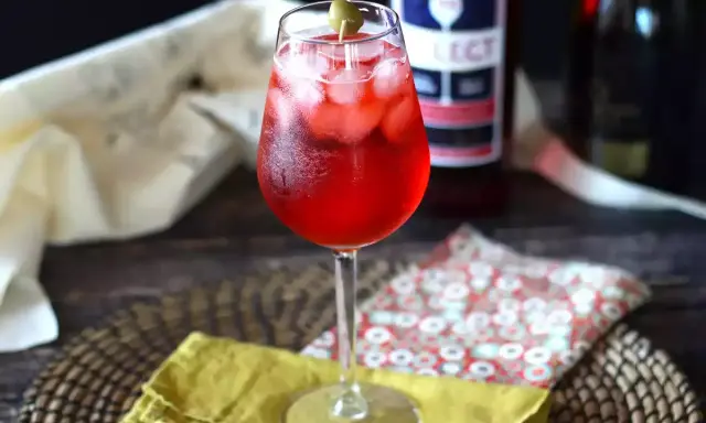 Un verre de spritz vénitien, rafraîchissant et pétillant, garni d'une olive. Parfait pour un apéritif ensoleillé.
