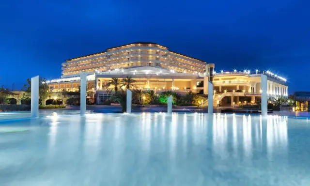Elegancki Starlight Resort Hotel nocą, z oświetlonym basenem i palmami.