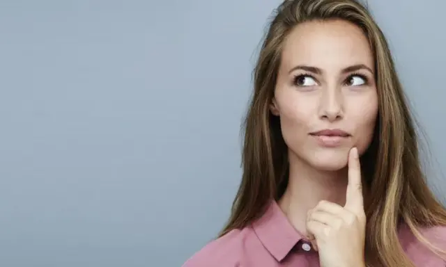 Nachdenkliche Frau mit langen Haaren, die über die Vorteile von Keratin und Kreatin für die Haargesundheit sinniert.